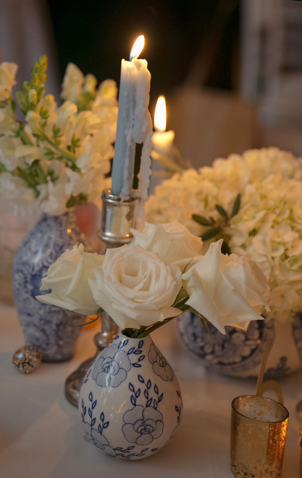 Florals in small vases, illuminated by candles during Maine wedding reception.