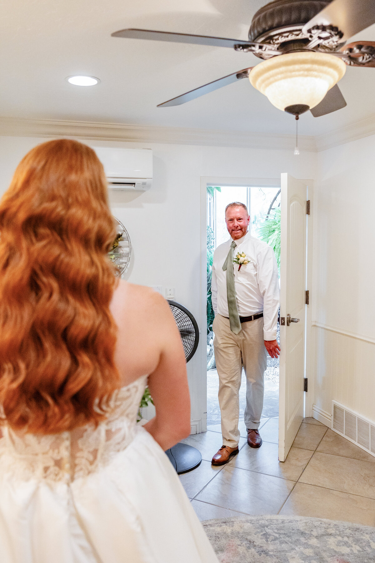 A father enters the room with an emotional expression as he sees his daughter in her wedding dress for the first time.
