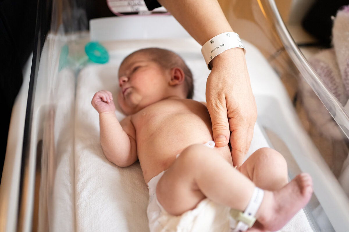 Newborn baby in diaper laying in bassinet