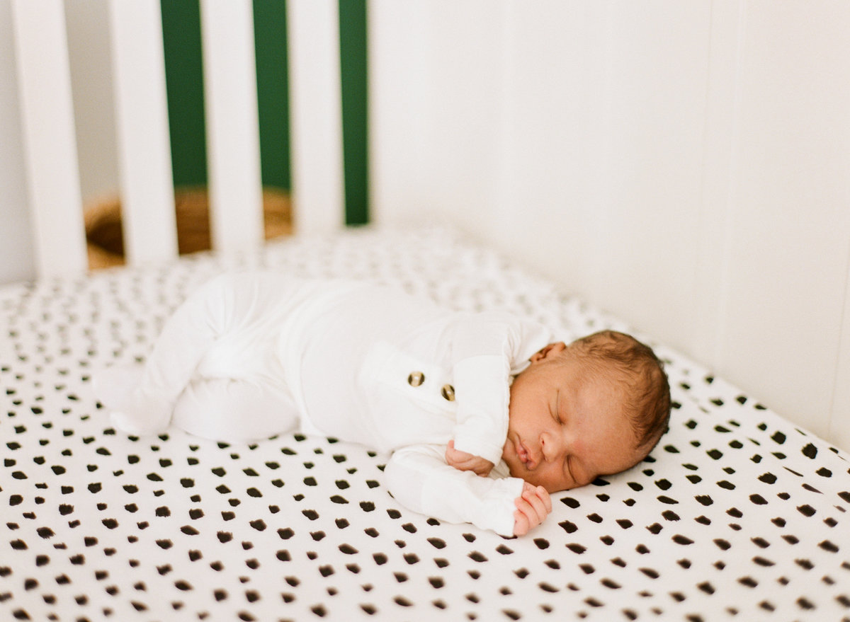 Black baby boy sleeps on a polka dot crib sheet during his newborn session in Raleigh.  Photographed by newborn photographers Raleigh A.J. Dunlap Photography.