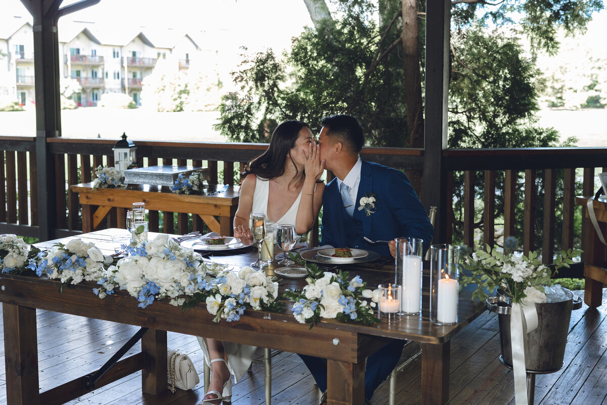 Bride and groom smiling at sweetheart table during wedding dinner