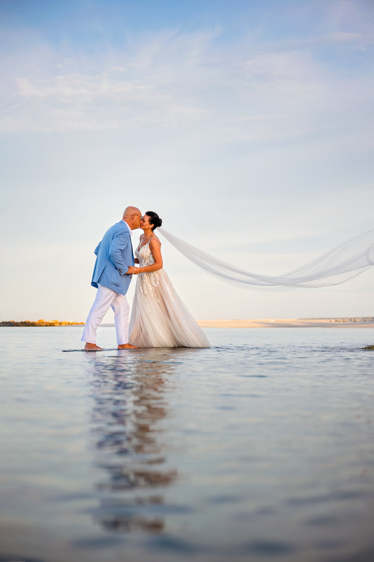 reflection of Bride and groom kissing in the ocean