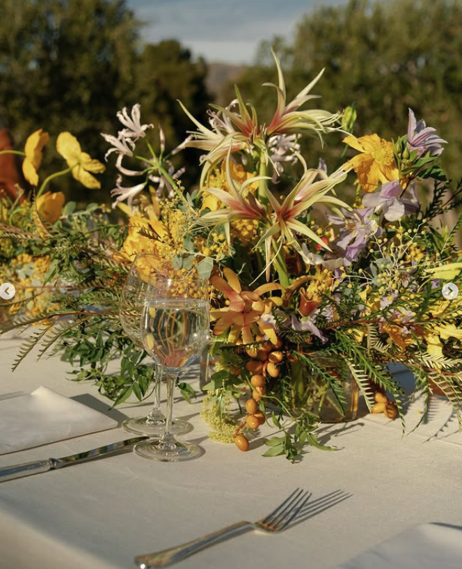 Delicate wildflower centerpiece in yellow and mauve hues, a romantic tablescape look inspired by Airlie Gardens weddings