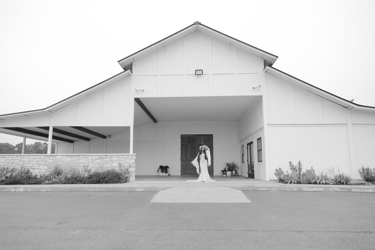 Exterior view of The Videre Estate wedding venue in Austin outside the stables lodge, with a country bride in boho attire.