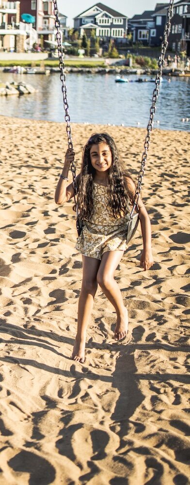 a little girl in a yellow dress is sitting on a swing
