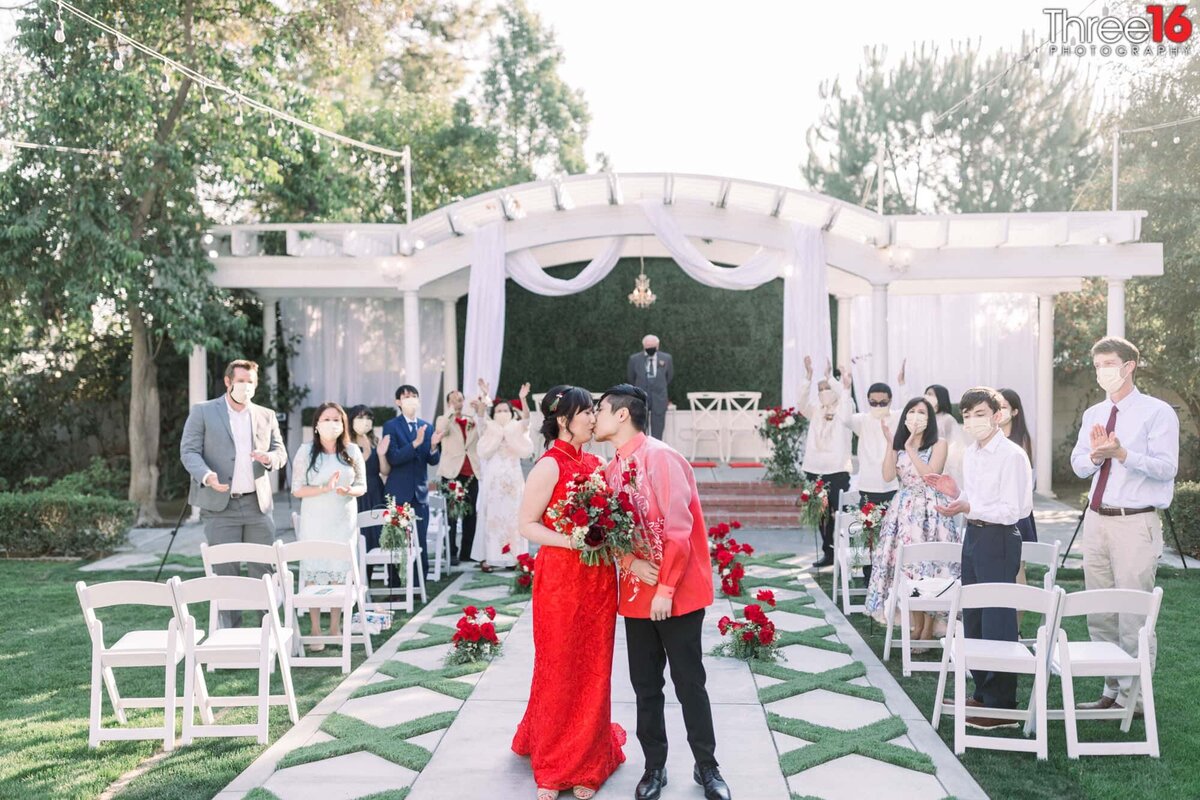 Newly married couple share a kiss at the end of the aisle