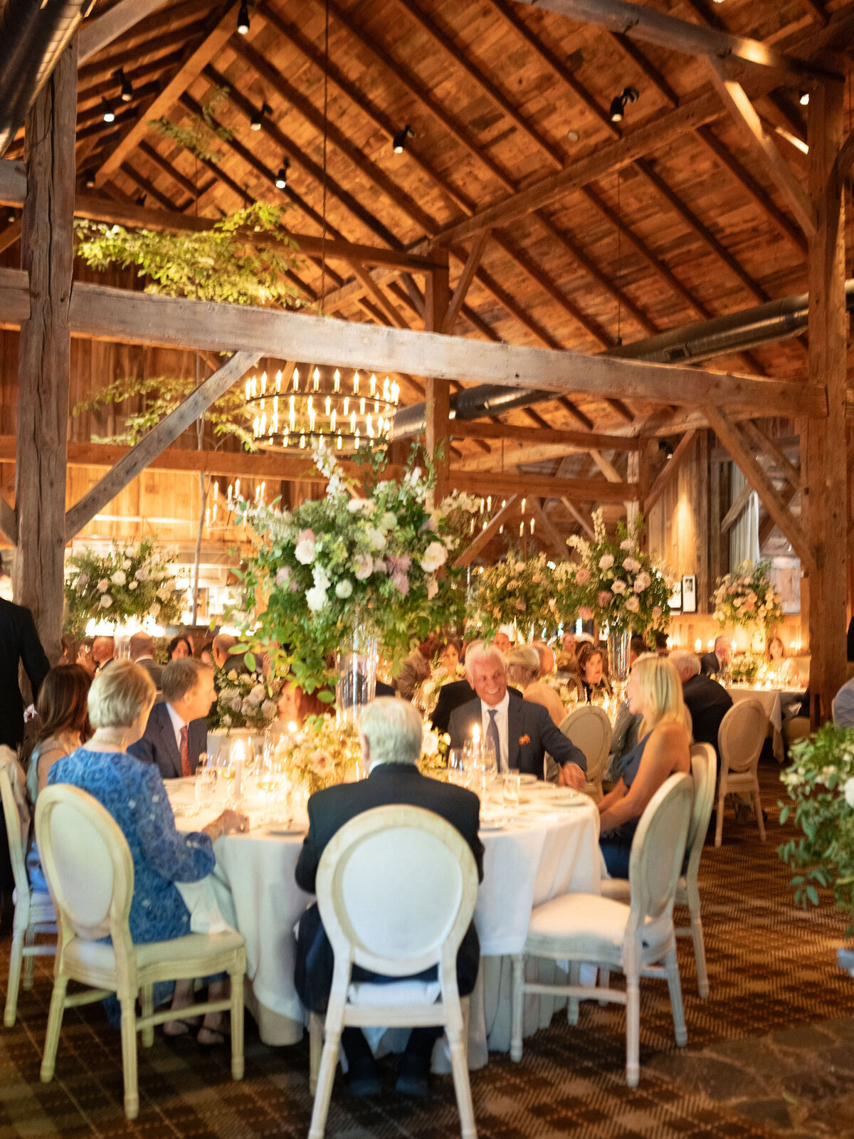 Elegant and timeless floral design for wedding reception tables. Wedding dinner at The Barn on Blackberry Farm. Garden inspired growing floral in colors of cream, white, blush, and green. Whimsical floral design for low centerpieces and elevated arrangements at fall wedding reception. Romantic candlelight and timeless floral design for elegant tablescapes. Destination wedding at Blackberry Farm. Design by Rosemary & Finch Floral Design in Nashville, TN.
