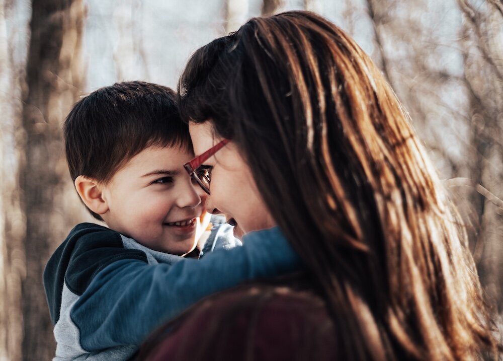 Edmonton mom with glasses holds her son up close to her face as they hug