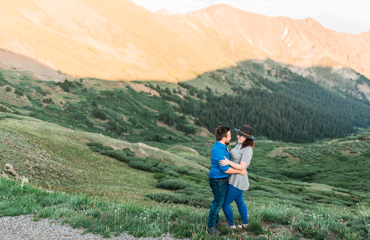 colorado engagement photos in the Rockies with man and woman embracing each other in the mountains as the sun sets in the distance