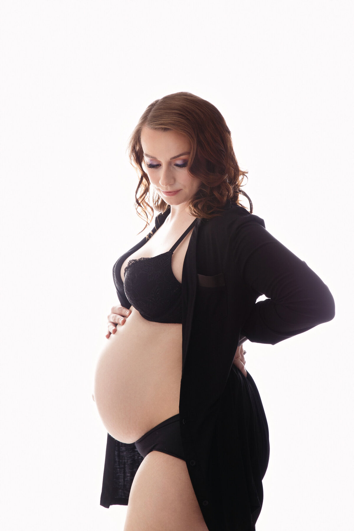 Studio shot of a beautiful pregnant woman wearing a black shirt and showing her baby belly