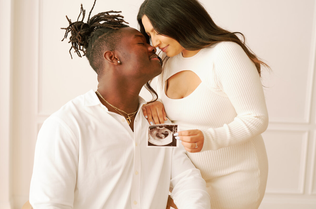 Couple posing with sonogram at a photography studio The Lumen Roomin Dallas Texas