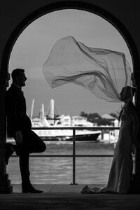 Romantic wedding silhouette by St Augustine wedding photographer showing bride's flowing veil through historic archway overlooking marina