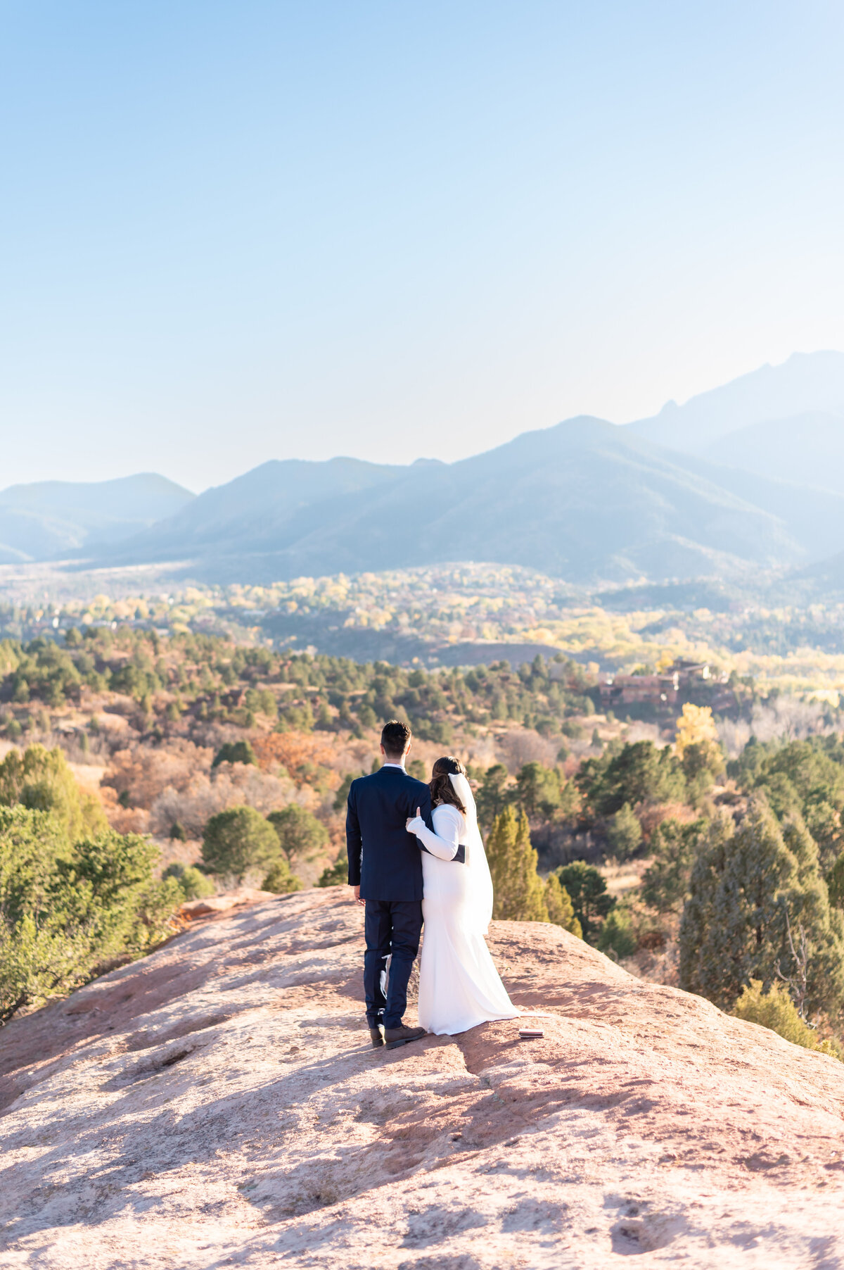 Bride and Groom standing on rock looking out into the mountains in Colorado Springs