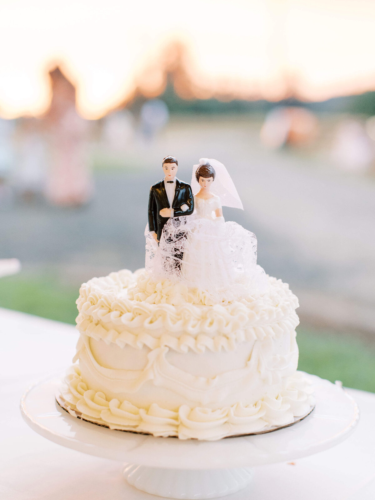 A white wedding cake with a bride and groom wedding topper.