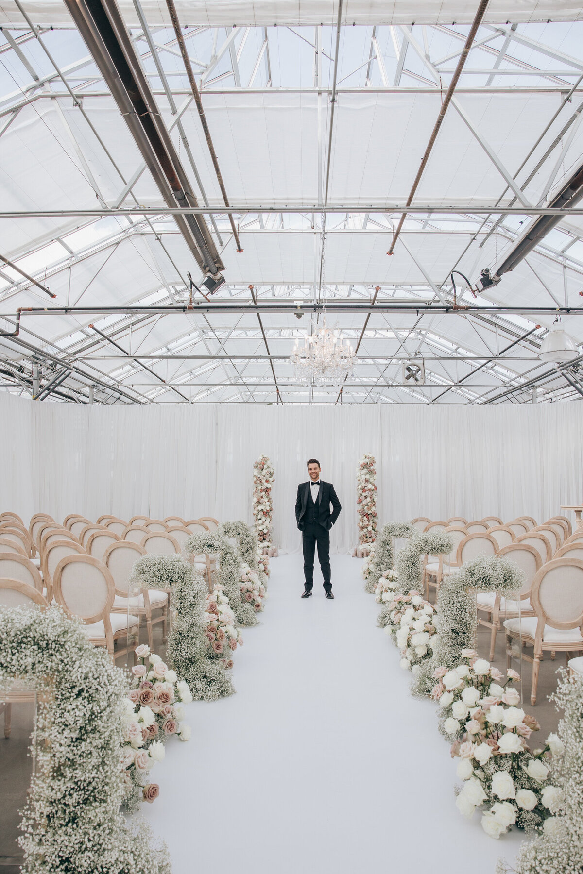 Wedding designer standing in wedding aisle full of romantic roses and baby's breath