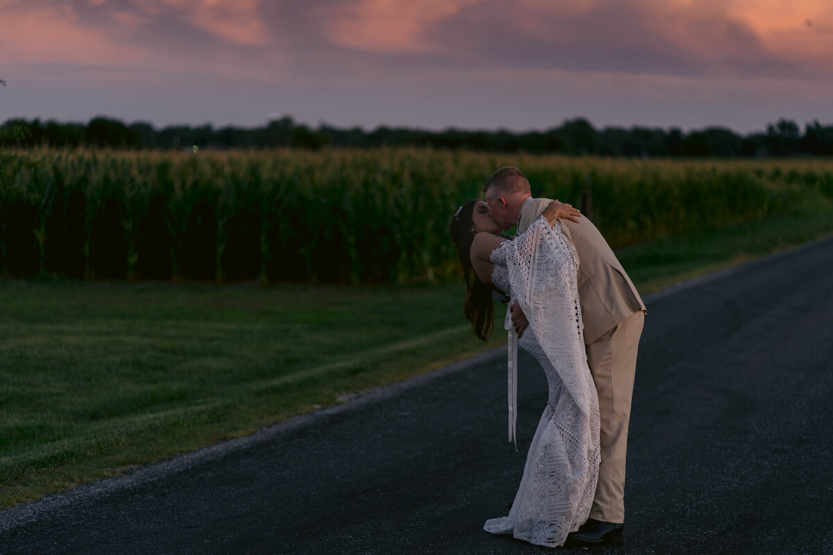 couple kissing by fields at sunset