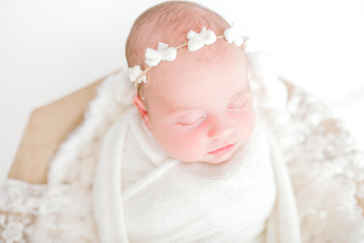 Baby in all white, light wood bowl with headband