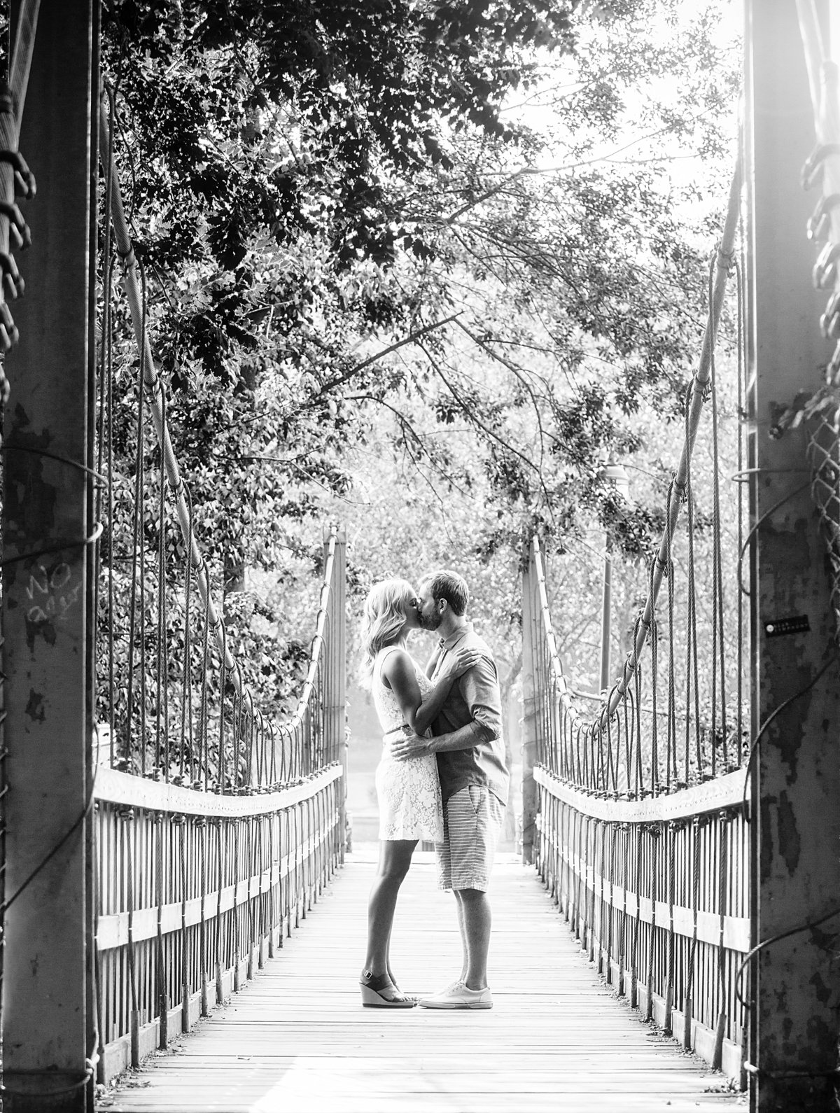 Charlotte engagement session with Jamie Lucido a black and white image of an engaged couple embracing on a bridge.