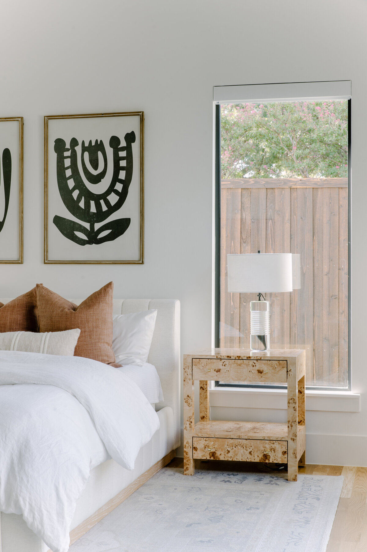 Well designed bedroom of a Dallas home  with a burl nightstand and large window