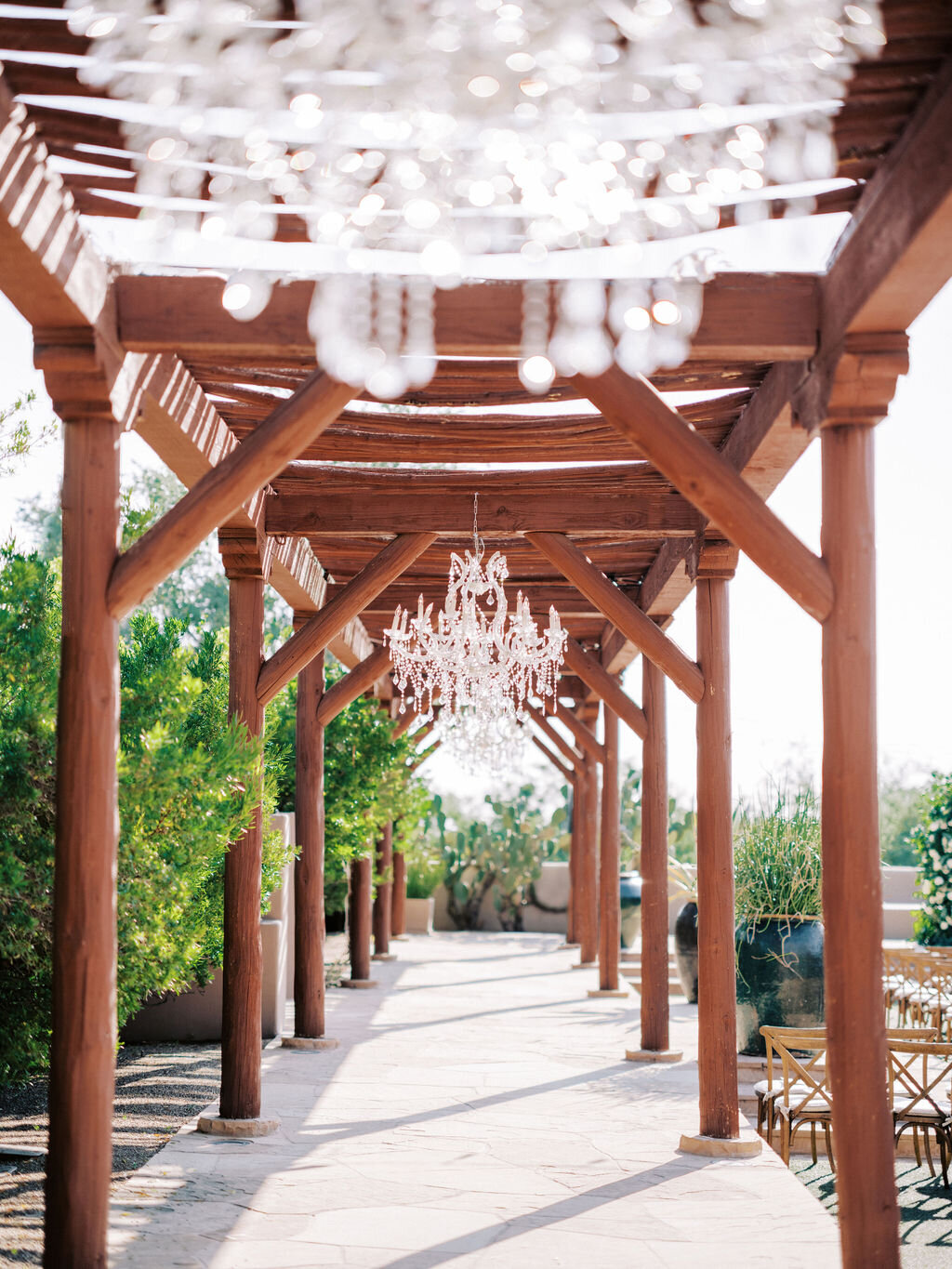 A dreamy wedding venue featuring a rustic pergola, sparkling chandeliers, and an intimate outdoor setting. The perfect spot for a luxury wedding celebration.
