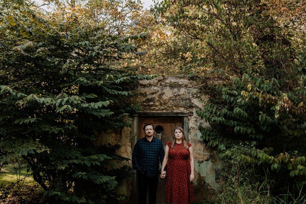 Bride and groom holding hands looking at each other while standing in front of rolling hills with the sunlight coming down on them