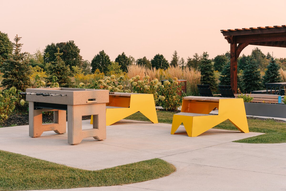 An outdoor lounge area featuring a foosball table, a seating area and lush landscaping