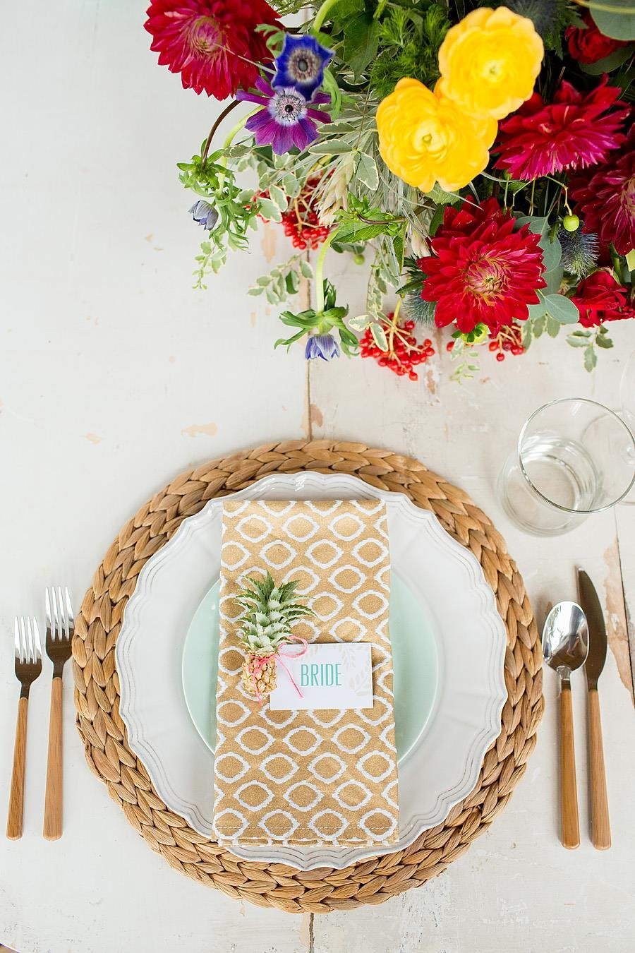 tropical table setting with mini pineapple and bright flowers