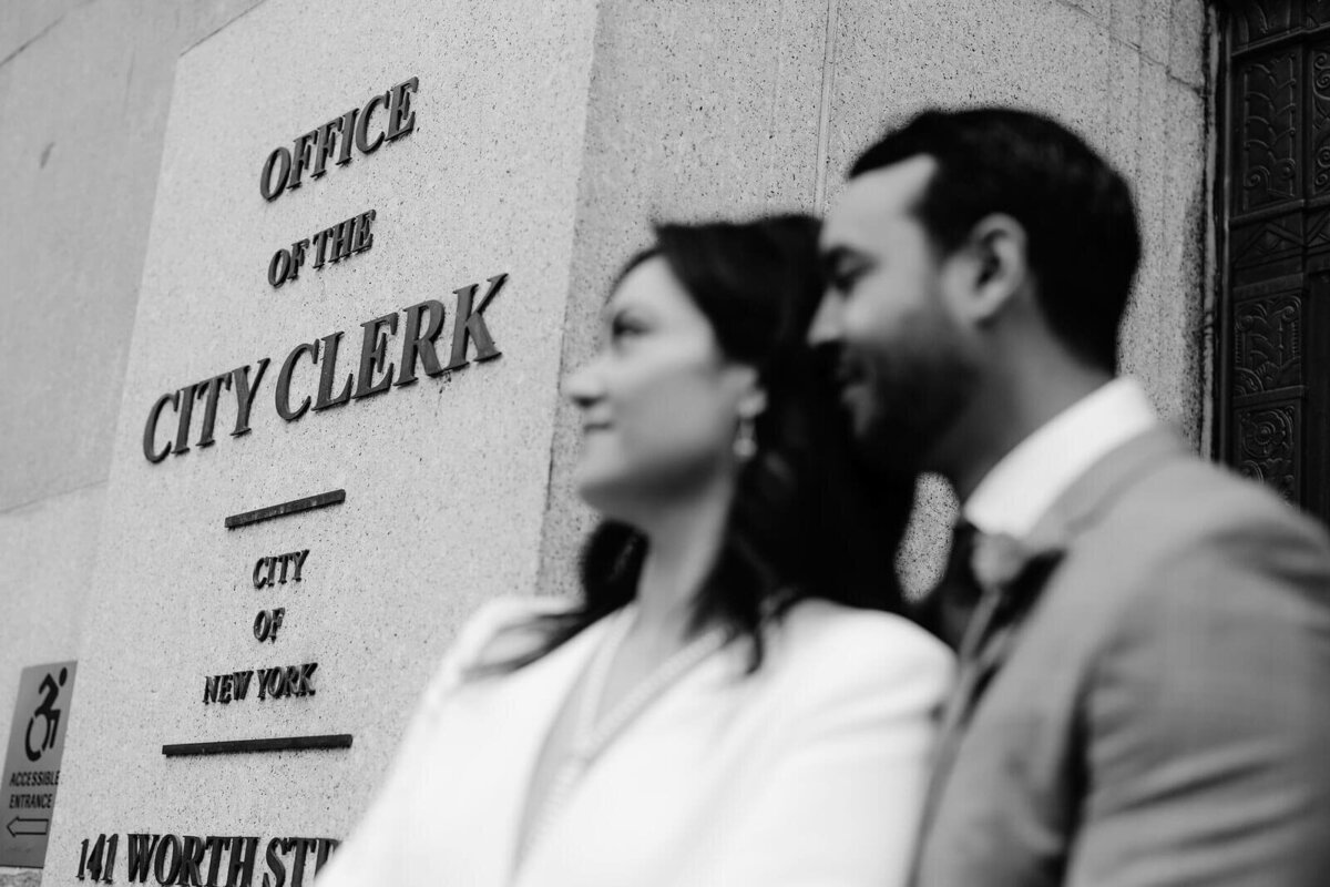 Black and white photo of the bride and the groom in front of NYC Office of the City Clerk for their elopement. Image by Jenny Fu Studio