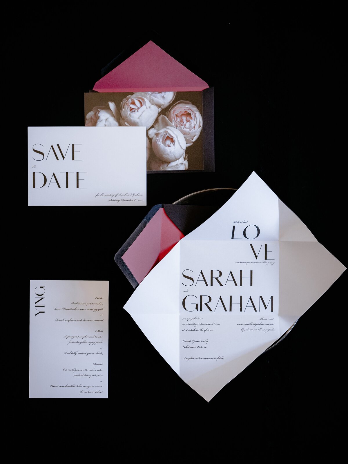 Bold and dark wedding invitations with large block text and dark pink roses, with place card menu and save the date card