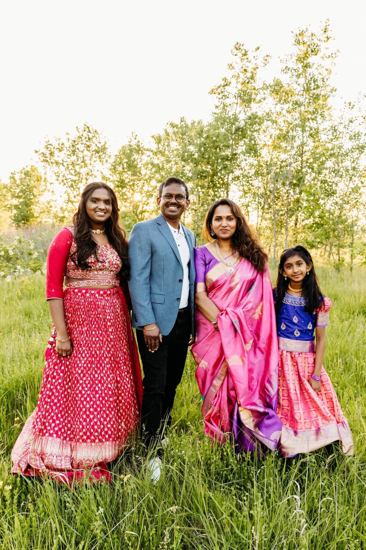 gorgeous family dressed in traditional Indian clothing and standing in a grassy field by Ashley Kalbus Photography