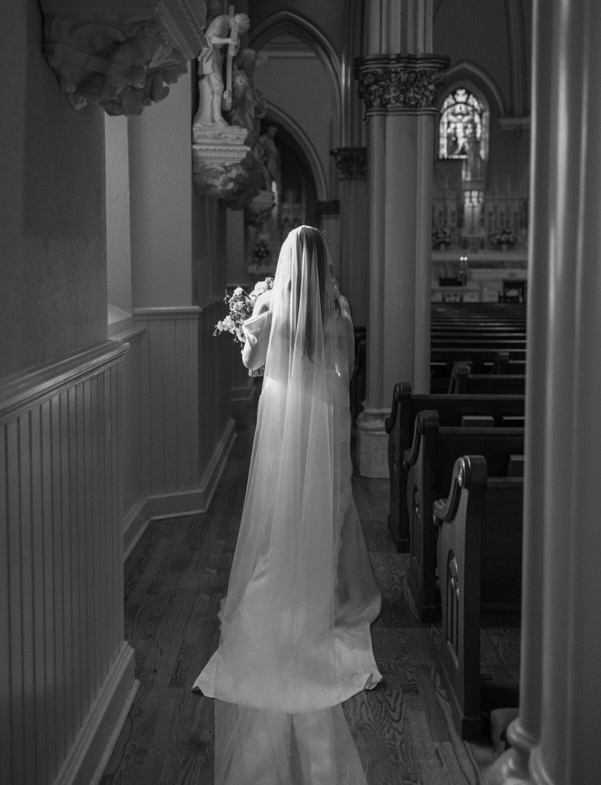 bride in long veil moves through sunlight in ornate cathedral, Detroit