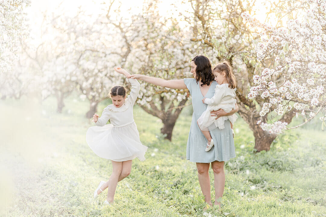 Candid lifestyle shot of girl twirling in cherry blossom orchard, captured by Brisbane Family Photographer Hikari.