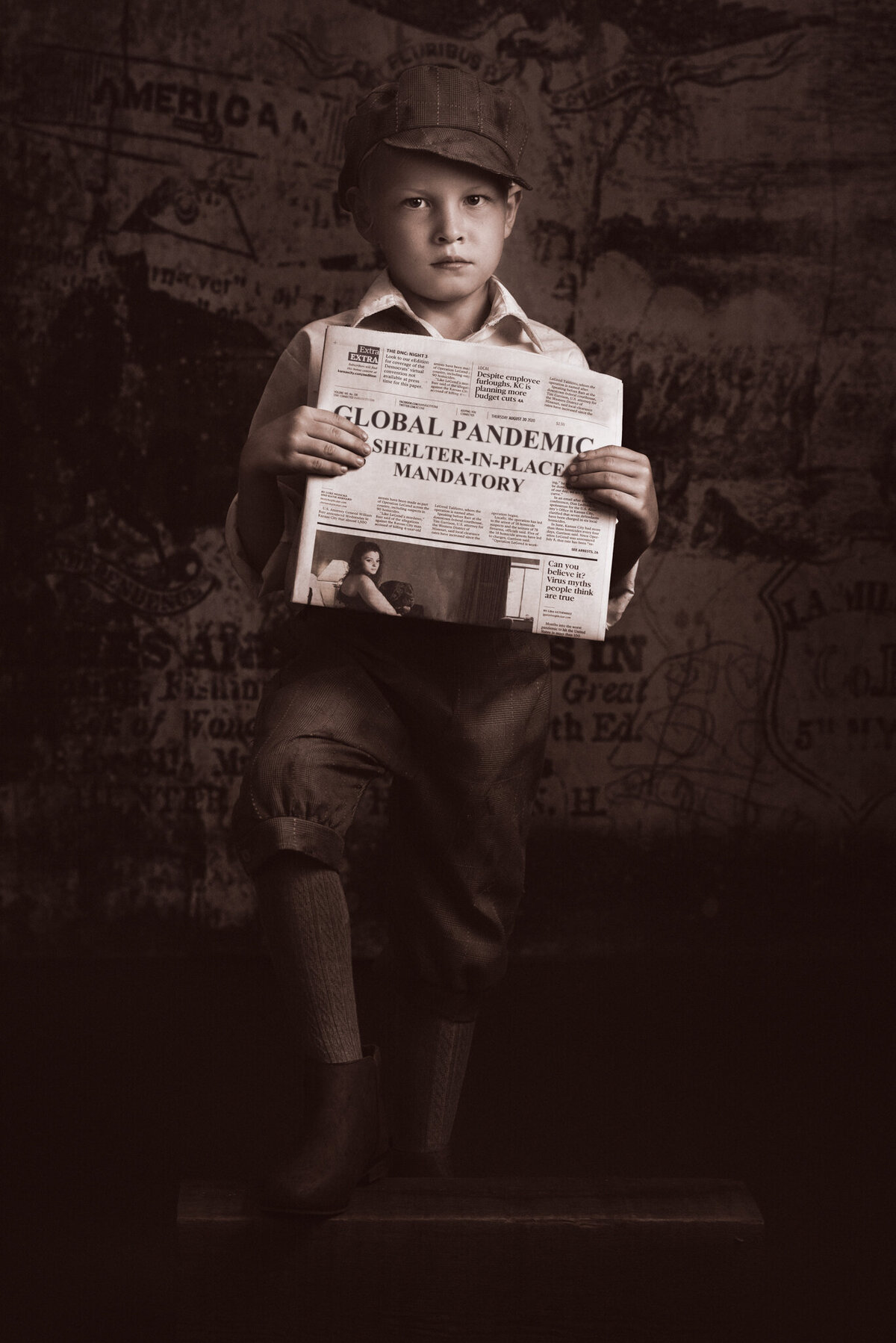 Timeless portrait of a young child dressed as a vintage newsboy, holding a newspaper against a dramatic sepia backdrop. Captured in Overland Park, Kansas, this nostalgic setup is perfect for families seeking classic and artistic child photography