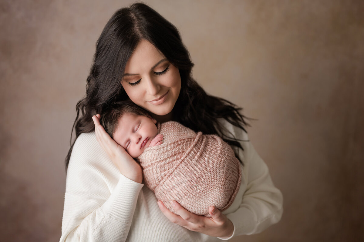 Baby girl held safely by mom in Houma newborn photography studio