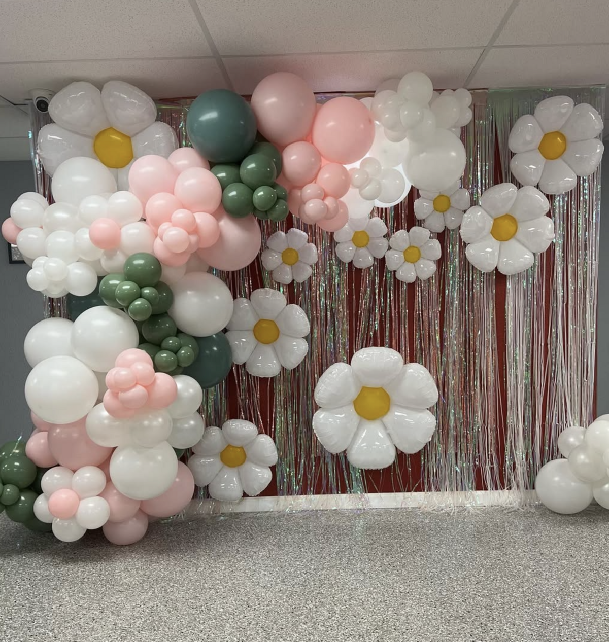 pink and white balloon installation with floral accents for children's events.