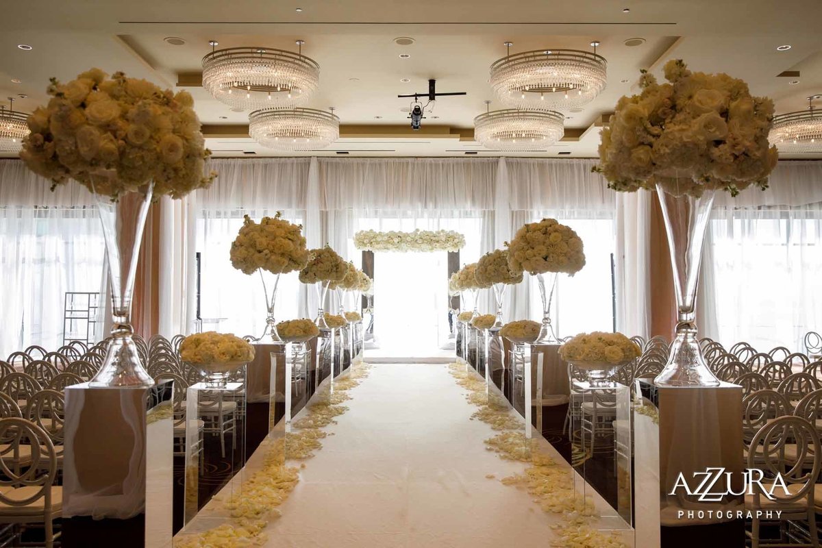 Wedding ceremony at Four Seasons Seattle with white aisle runner, white rose petals, large white flower arrangements on top of mirrored pedestals