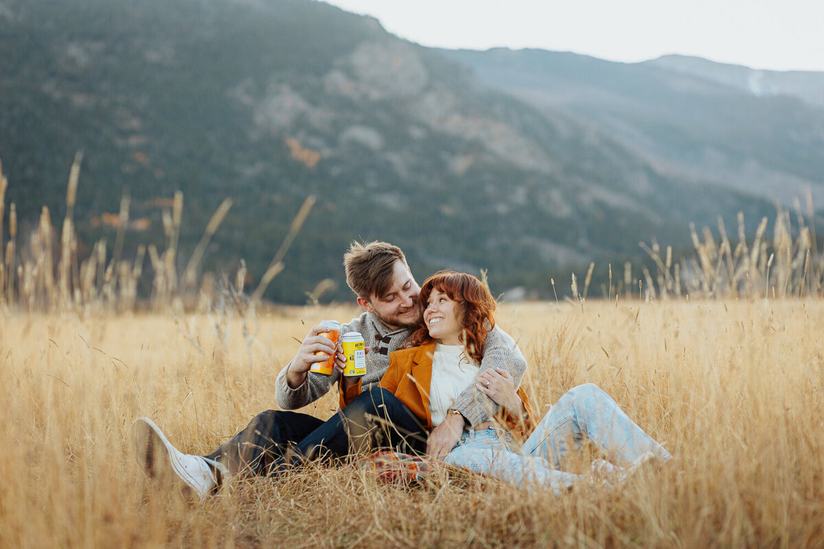 An engaged couple sits and enjoys their favorite beer in Rocky Mountain National Park in Estes Park, Colorado.