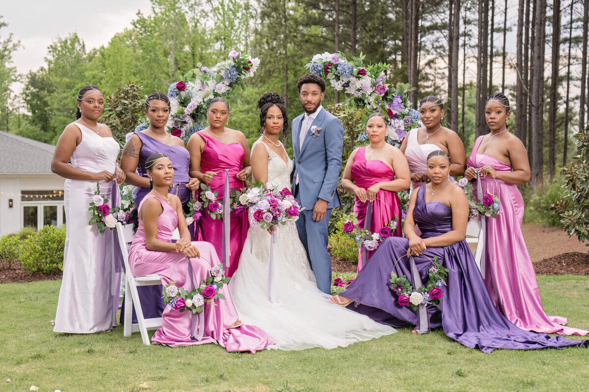Vibrant wedding party posing with the bride and groom at a stylish outdoor wedding celebration.