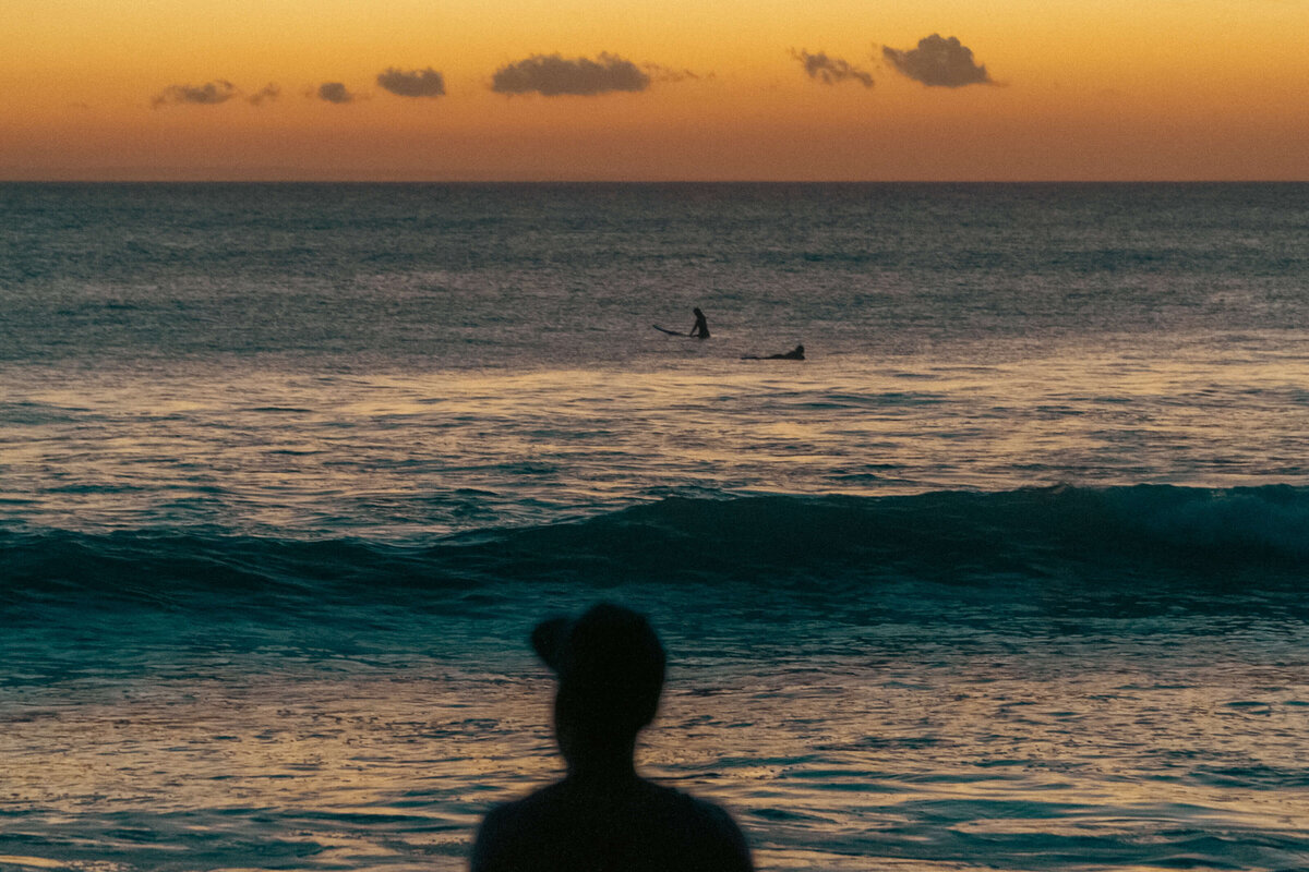 Sunset ocean view with a surfer in the distance