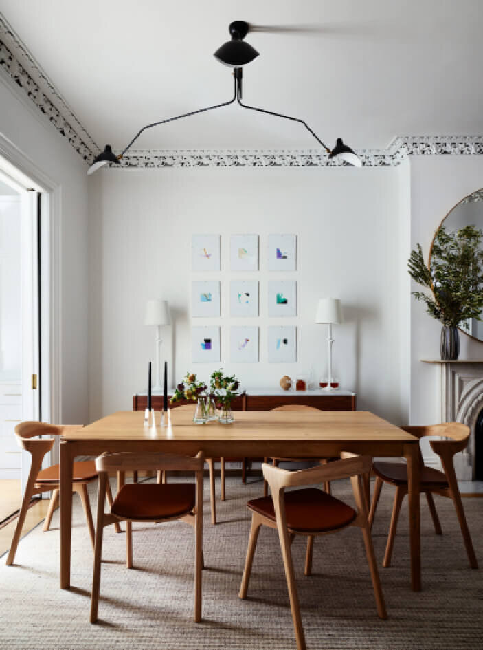 Interior Designers Boston MA designed a modern dining room with a natural wood table and chairs, mid-century modern lighting, and plaster white lamps.