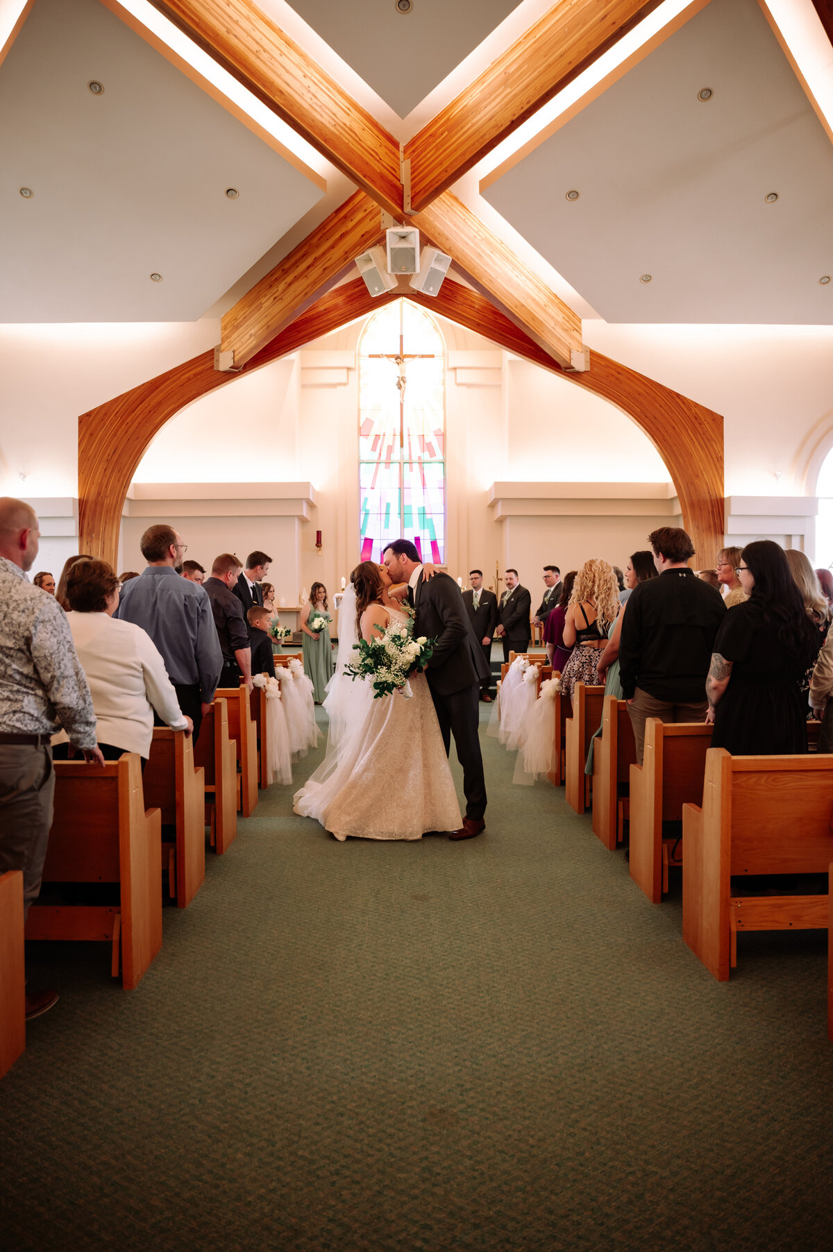 bride and groom kiss middle of the aisle as they walk