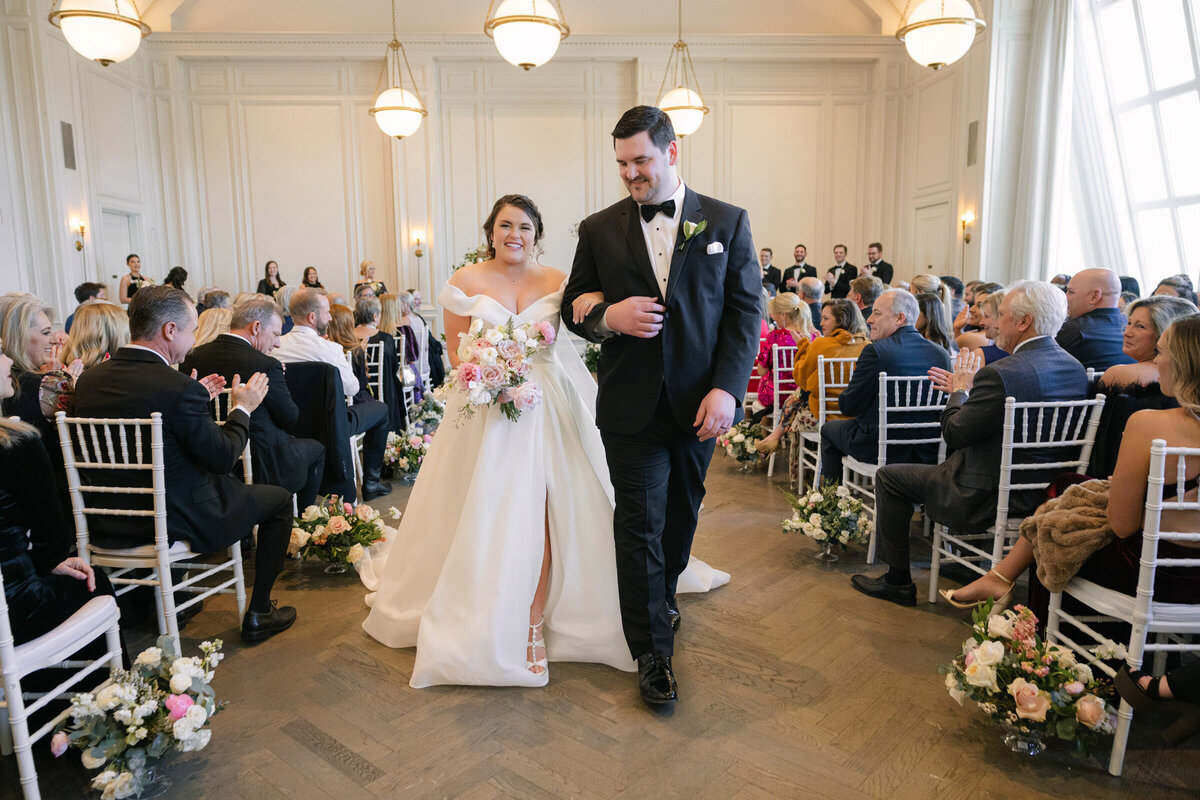 bride and groom walking down the aisle happily after being pronounced husband and wife in the Governor’s Room at The Adolphus in Dallas, capturing a joyful and celebratory wedding moment.