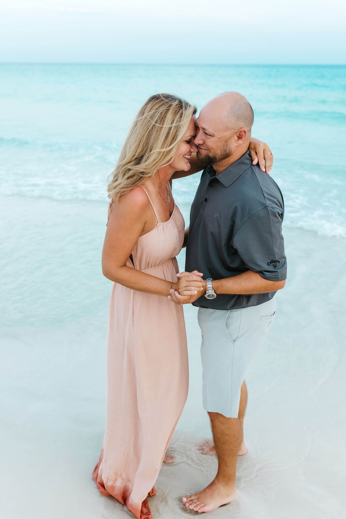 Family portrait of husband and wife dancing on the shoreline in Destin, FL