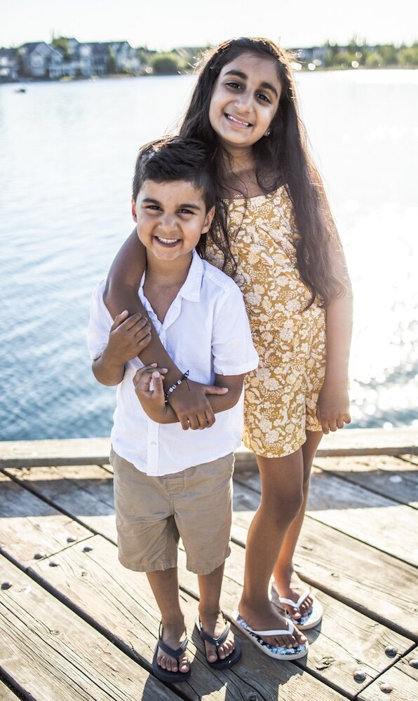 Big sister is is holding her younger brother in a hug