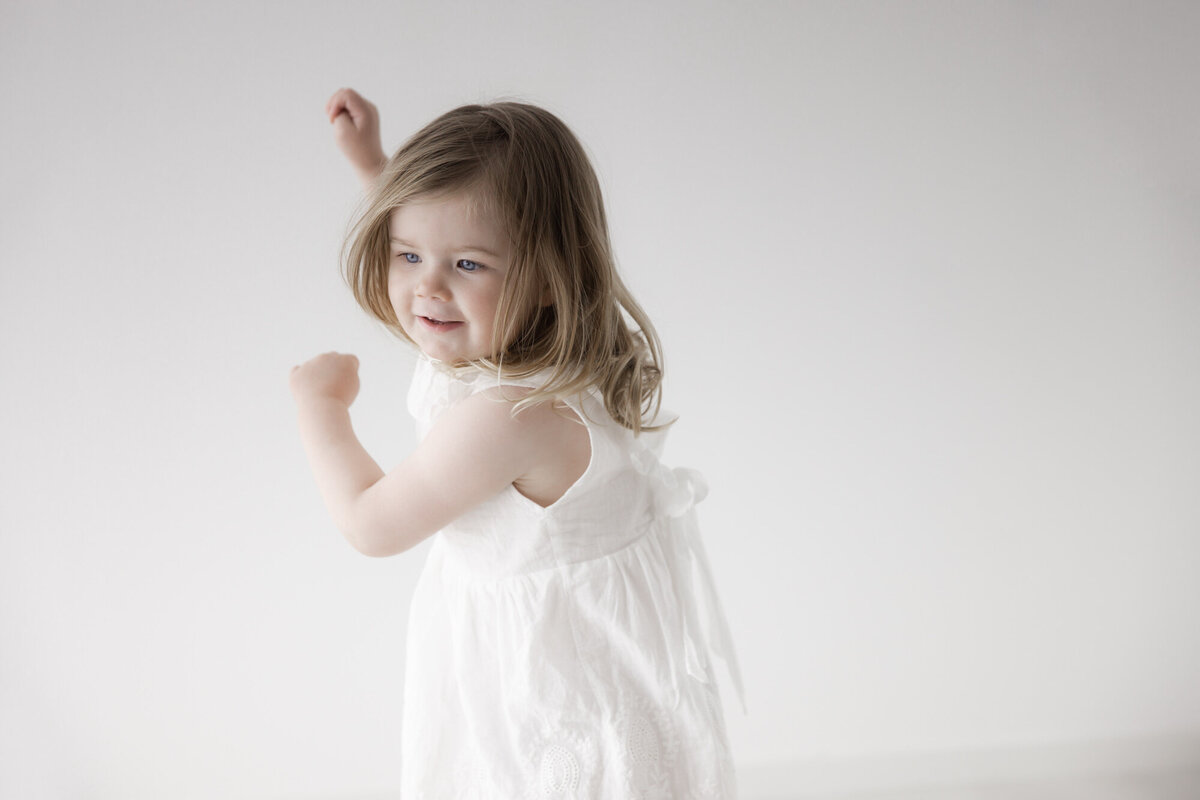 En treårig jente danser i studio, iført en hvit kjole. Fotografert i Studio Landmark, Fyllingsdalen.