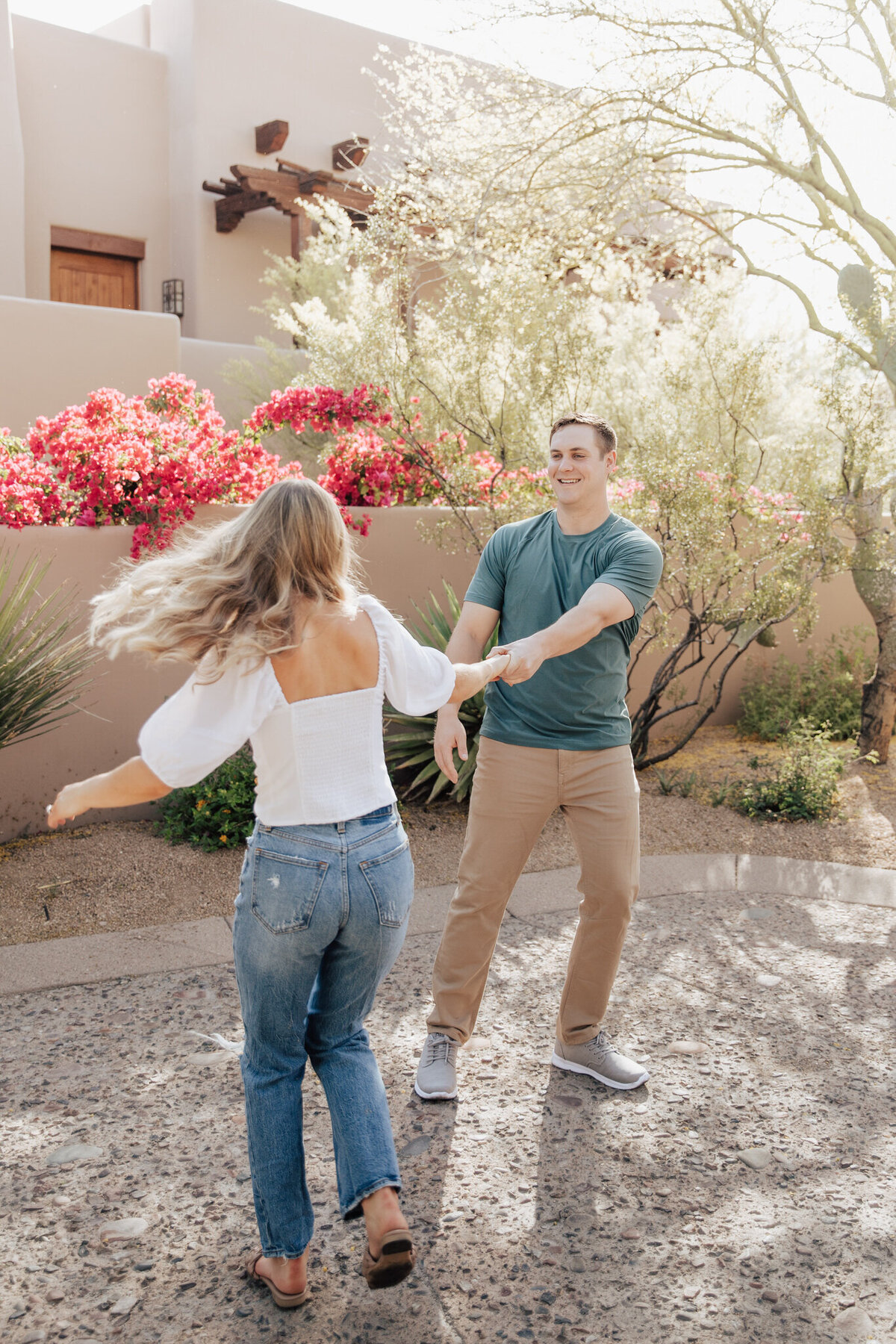Couple laughing holding hands with pink flowers in background at the Four Seasons Resort in Scottsdale, Arizona.