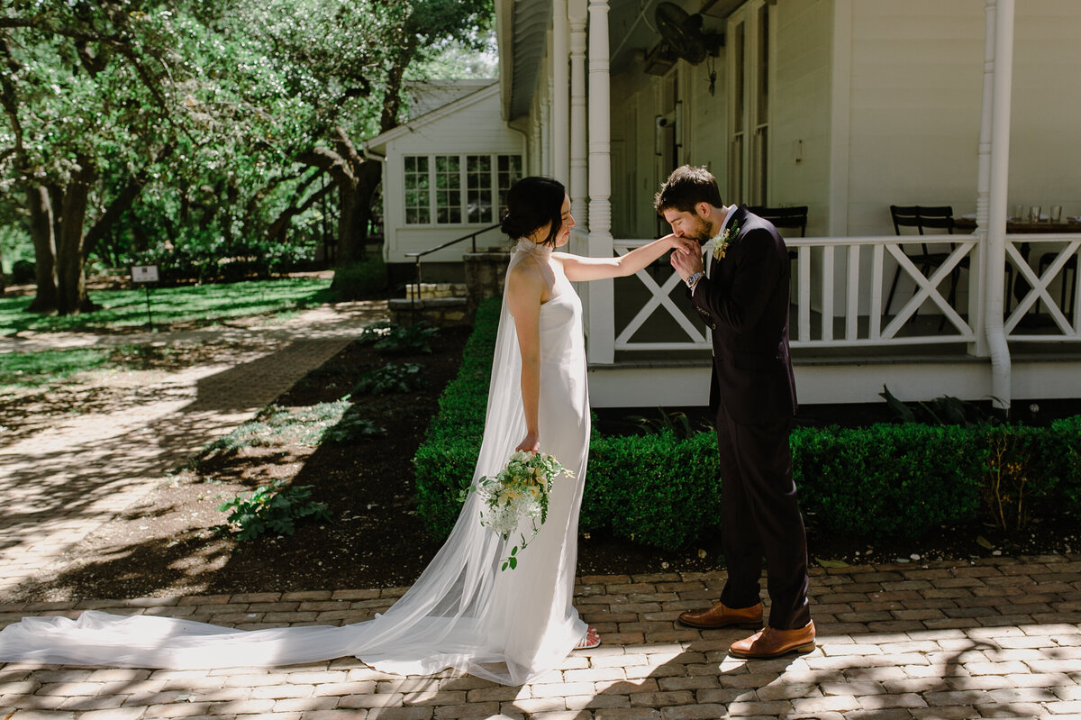 Groom kissing the hand of his bride at Mattie's  Austin Wedding