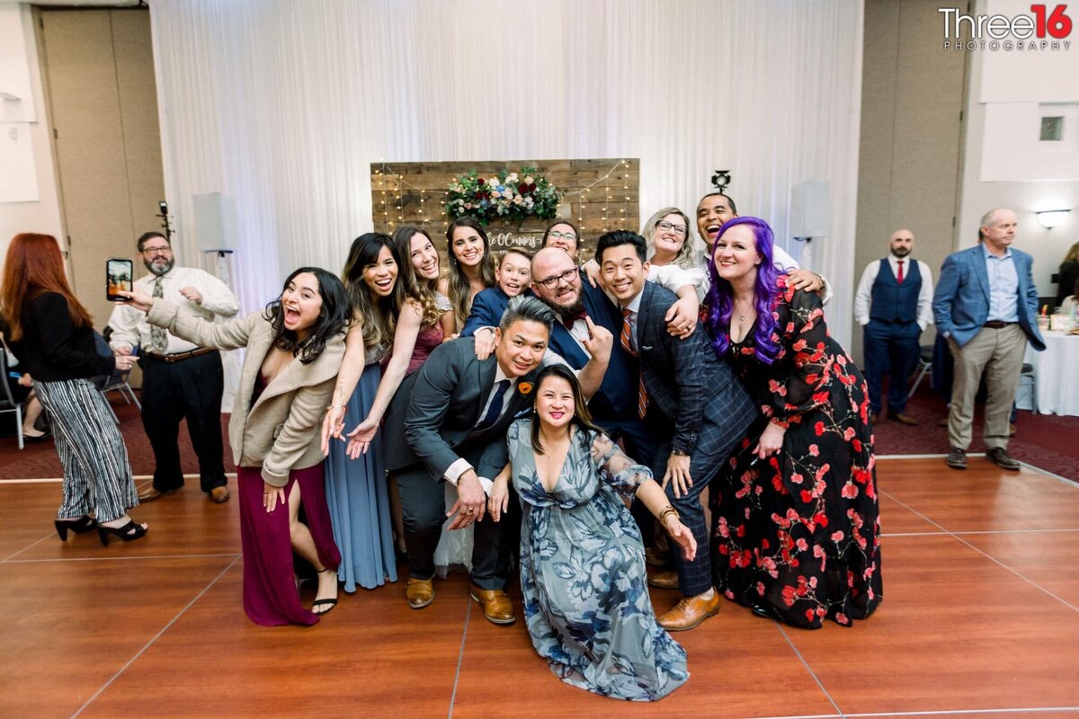 Bride and Groom pose in a tight group shot with guests