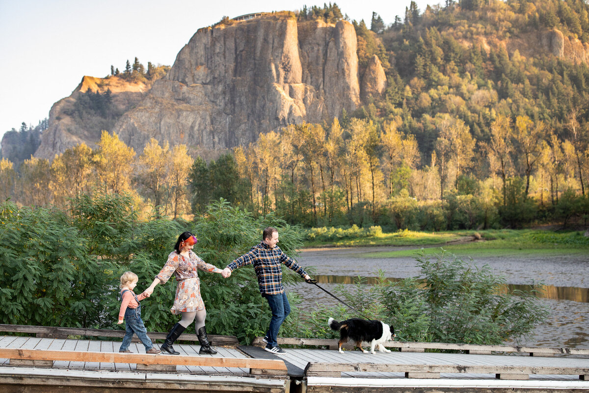 Family of three with dog walking on dock in the Columbia River Gorge. Portland family photography.