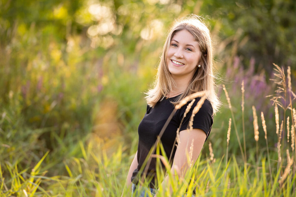 Ottawa family photography of a teenage daughter smiling in the long grass at sunset golden hour